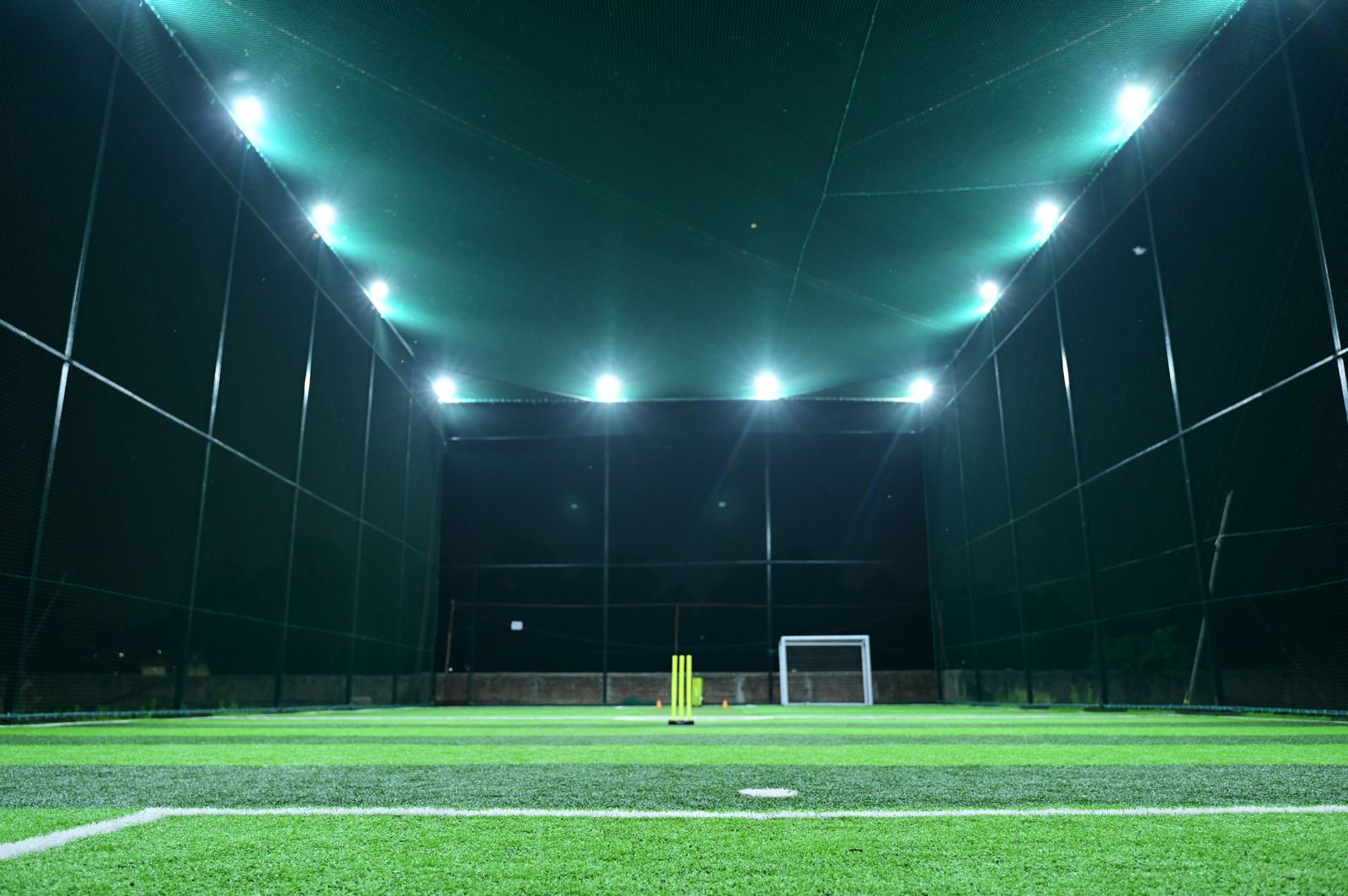Cricket stumps and goal at night at The Turf X